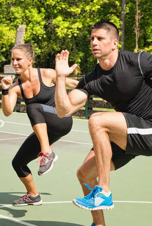 Couple performing knees to elbow in standing position