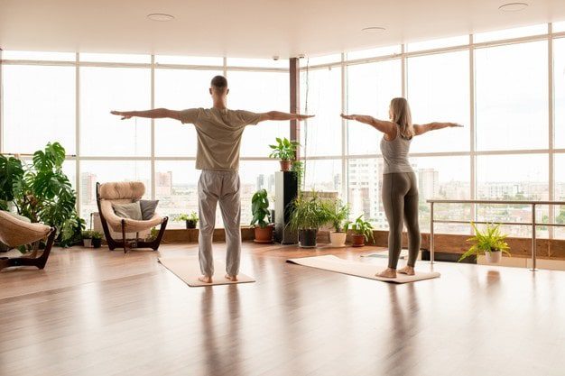 man and woman with arms outstretched during workout