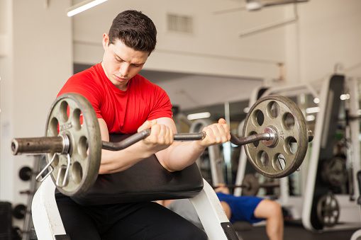 Man doing preacher curls at the gym