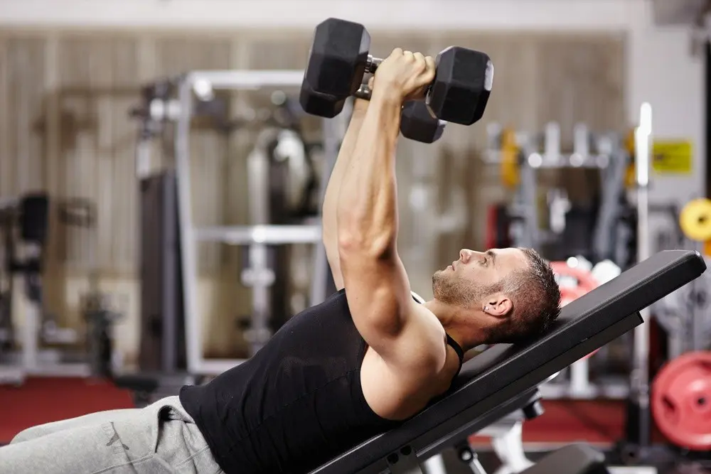 Man with dumbbells on bench doing upper-lower vs push-pull workout