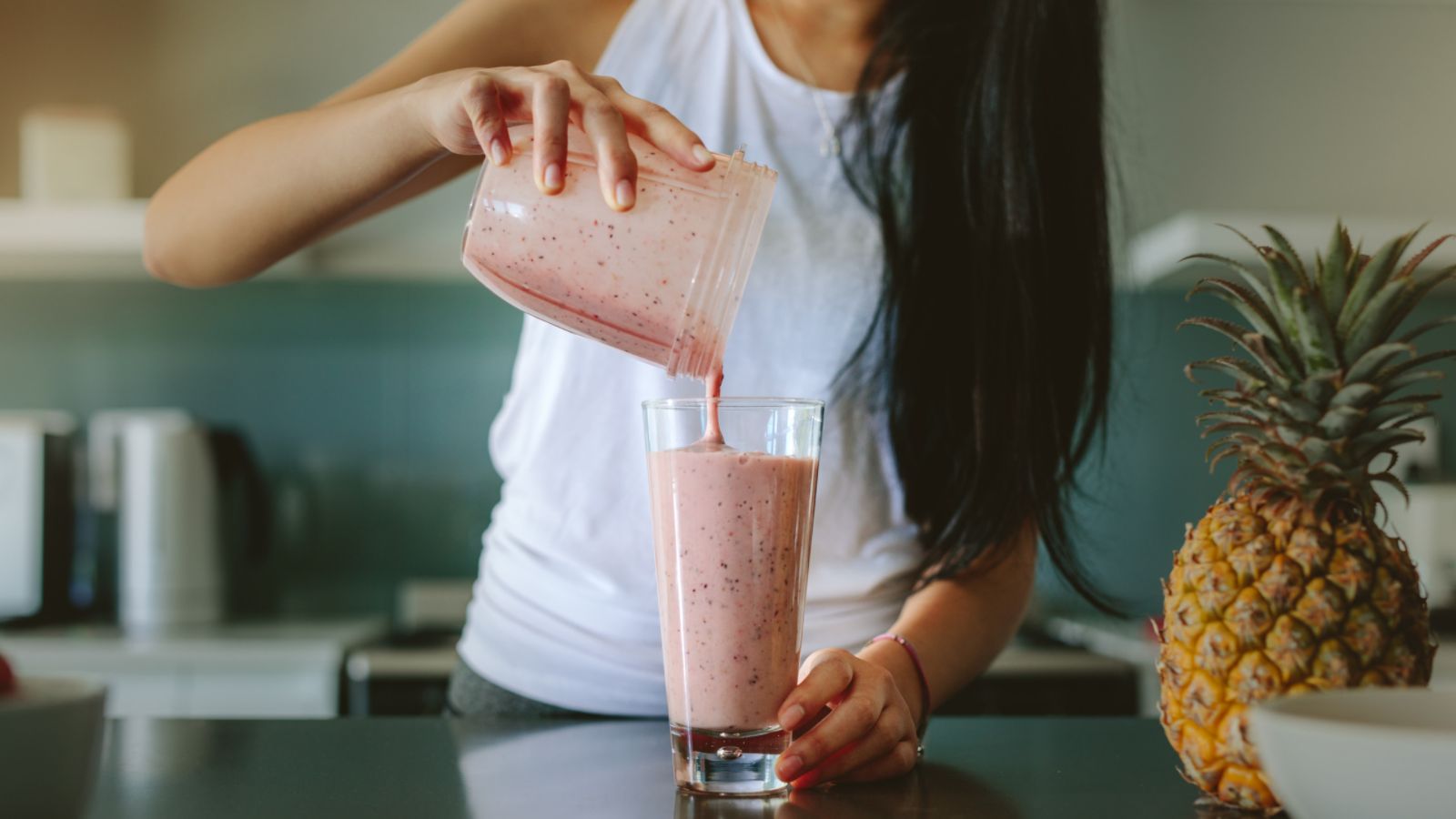 woman pouring smoothie in a glass