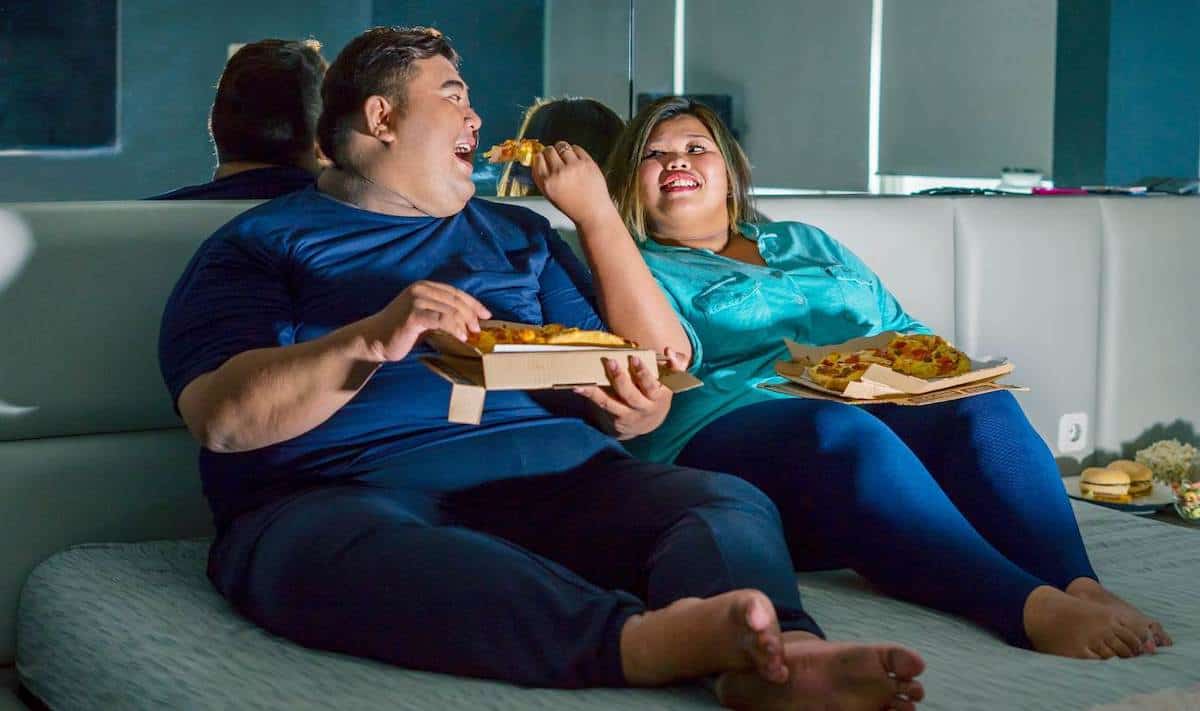 Obese couple eating in bed