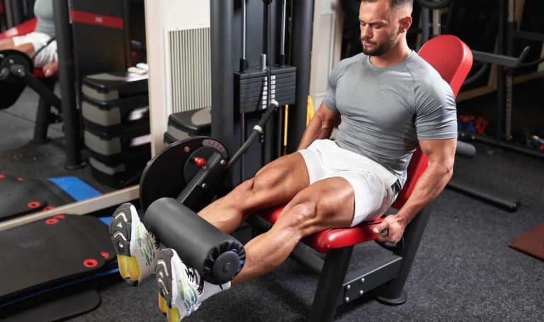 Man doing leg extensions in a 5 day push pull legs workout routine